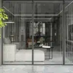 Modern floor-to-ceiling glass Lift & Slide Doors revealing a stylish living room next to a potted patio plant.