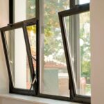 Modern black-framed Tilt & Turn Windows tilted open for ventilation, overlooking outdoor greenery.