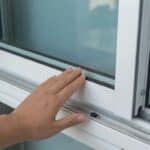 Close-up of a hand inspecting the weather seal along a white sliding window track, highlighting precision details during a Hurricane Window Installation.