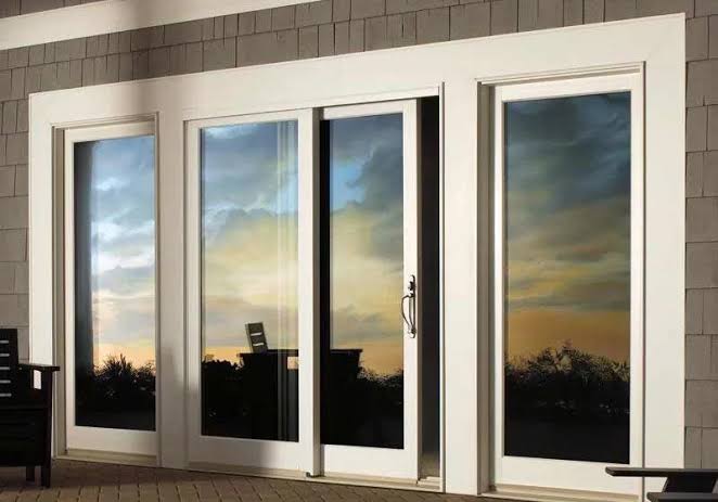 Modern white sliding glass patio doors reflecting the sunset sky, featuring Impact Windows Miami.