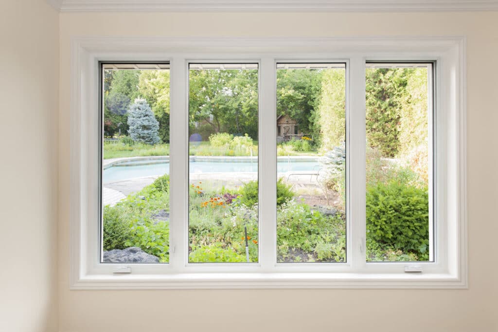Interior view looking through four white-framed windows out to a sunny backyard pool, offering dependable Storm Windows Hurricane Protection.