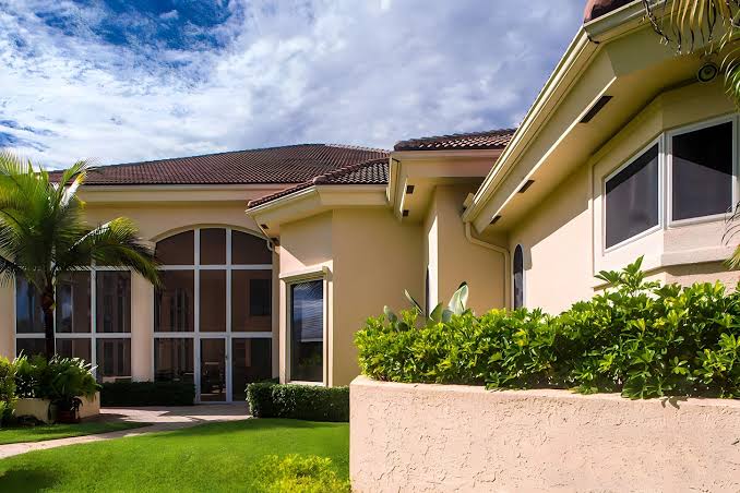 Exterior view of a luxury tropical home featuring tinted multi-pane glass windows designed for Storm Windows Hurricane Protection.